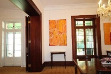 A picture of orange paintings in Kirribilli House next to dark stained wood furniture, window frames and doors