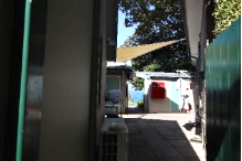 A picture of a narrow walk way outside the Kirribilli House with a green fence adjacent and awnings above shading the walk way