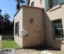A picture of brown splotches on the outside walls from damp pavers