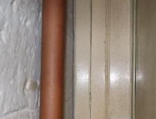 A picture of an orange pipe by a wall and doorway