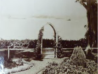 A black and white picture of an archway and gate by the gardens at Kirribilli House