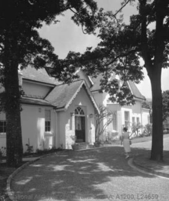 A black and white picture of the driveway leading to the Kirribilli House entryway, with two large trees on either side shading the entry.