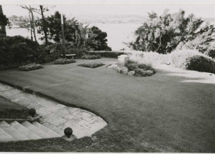 A black and white picture of large areas of grass across the Kirribilli House gardens with smaller surrounding bushes and larger trees in the distance