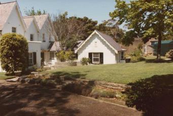 A picture of a raised lawn by Kirribilli House with trimmed grass and large trees shading the area