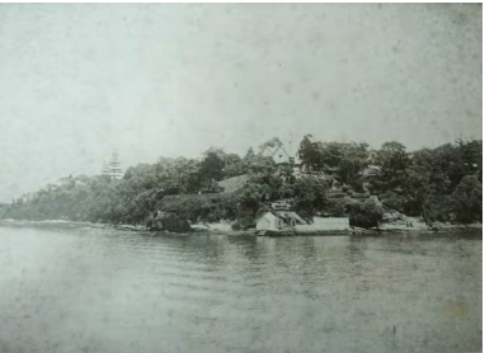 A black and white picture of Kirribilli House boat harbour surrounded by large trees and a body of water  
