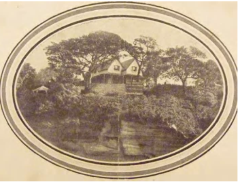 A sepia toned image of Kirribilli House from the harbour overlooking the cliff, trees, the house and its grounds. 