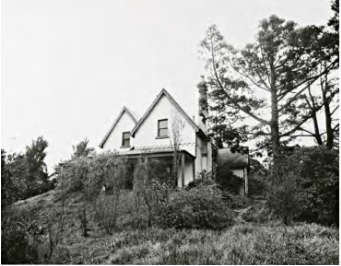 A black and white picture of Kirribilli House from a distance surrounded by overgrown grass, bushes and large trees