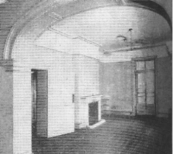 A black and white picture of an empty room at Kirribilli House under an arched entry way looking at the floor to ceiling window and fireplace