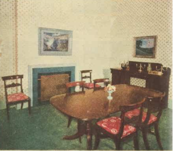 A picture of a dining room with a wood dining table, matching chairs with red cushions and a buffet adjacent to the table with candles on top. 